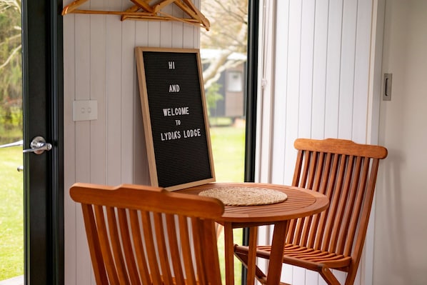 Une chaise et une table en bois, avec une pancarte de bienvenue, se trouvent au Lydia's Lodge.