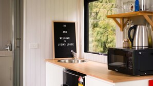 Et moderne køkken med træbordplade, en tavle, en vask, en mikrobølgeovn og udsigt til grøn natur.
