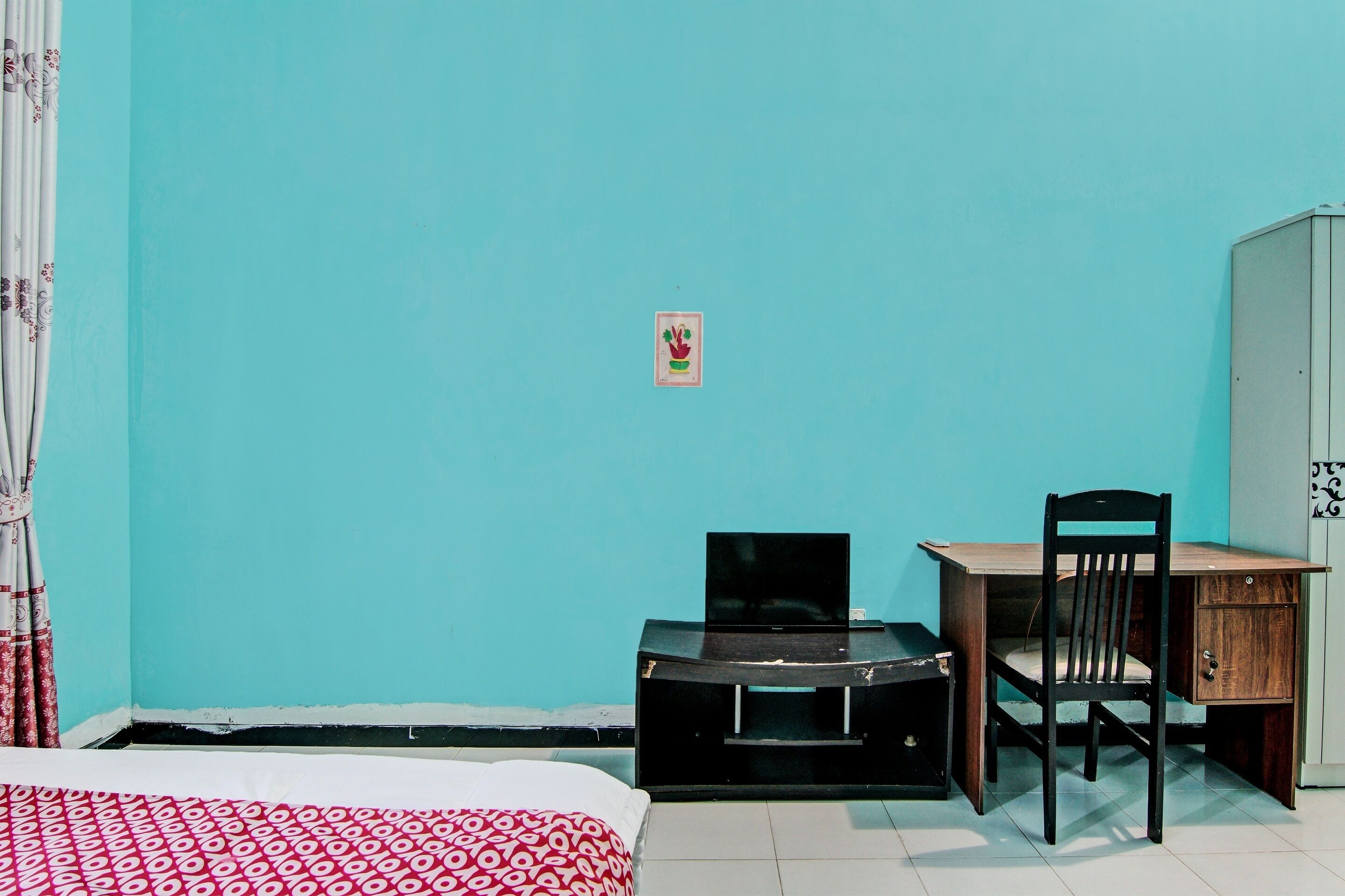 A room with a bed, a desk, a chair, and a television.