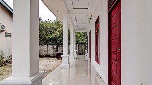 A corridor with white columns and a red door at the end.