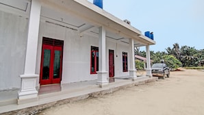 A building with a white facade, red doors, and blue water tanks on the roof.