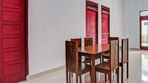 A dining area with a wooden table and chairs, red doors, and a tiled floor.