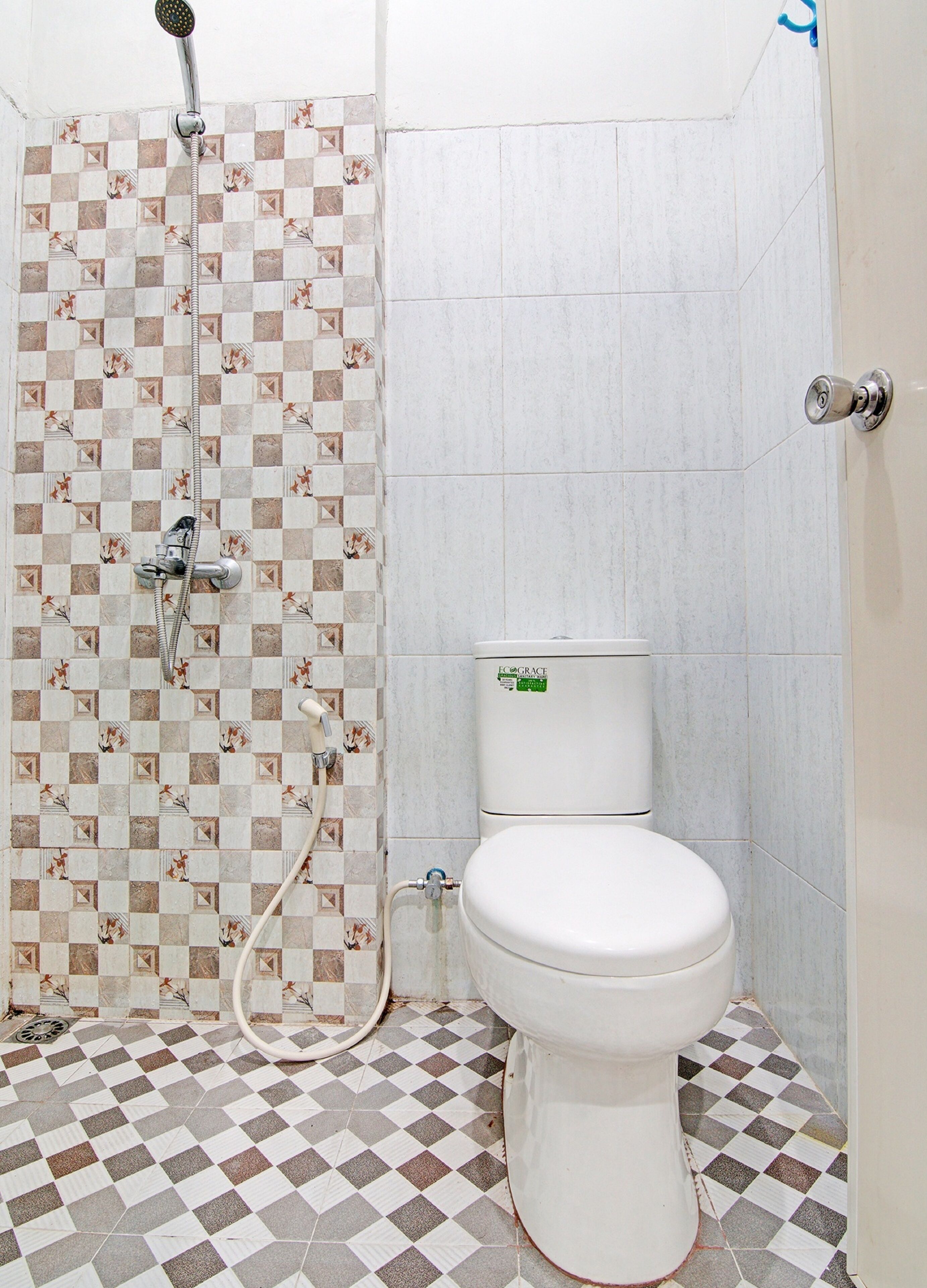 Een badkamer met douche, toilet en zwart-witte vloertegels.