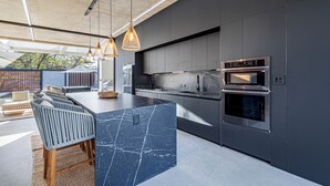 A modern kitchen with a marble island, stainless steel appliances, and pendant lighting. - Casa Uana, luxury new home in gated community, private pool, steps to the beach (Tamarindo)