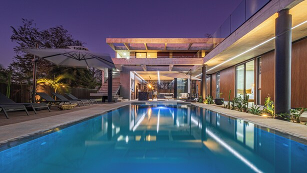 A modern pool area with a clear pool, sun loungers, and a contemporary building with large windows and a flat roof. - Casa Uana, luxury new home in gated community, private pool, steps to the beach (Tamarindo)