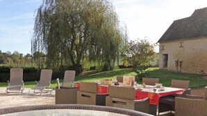 An outdoor hot tub area with wicker furniture and a dining table set for a meal.