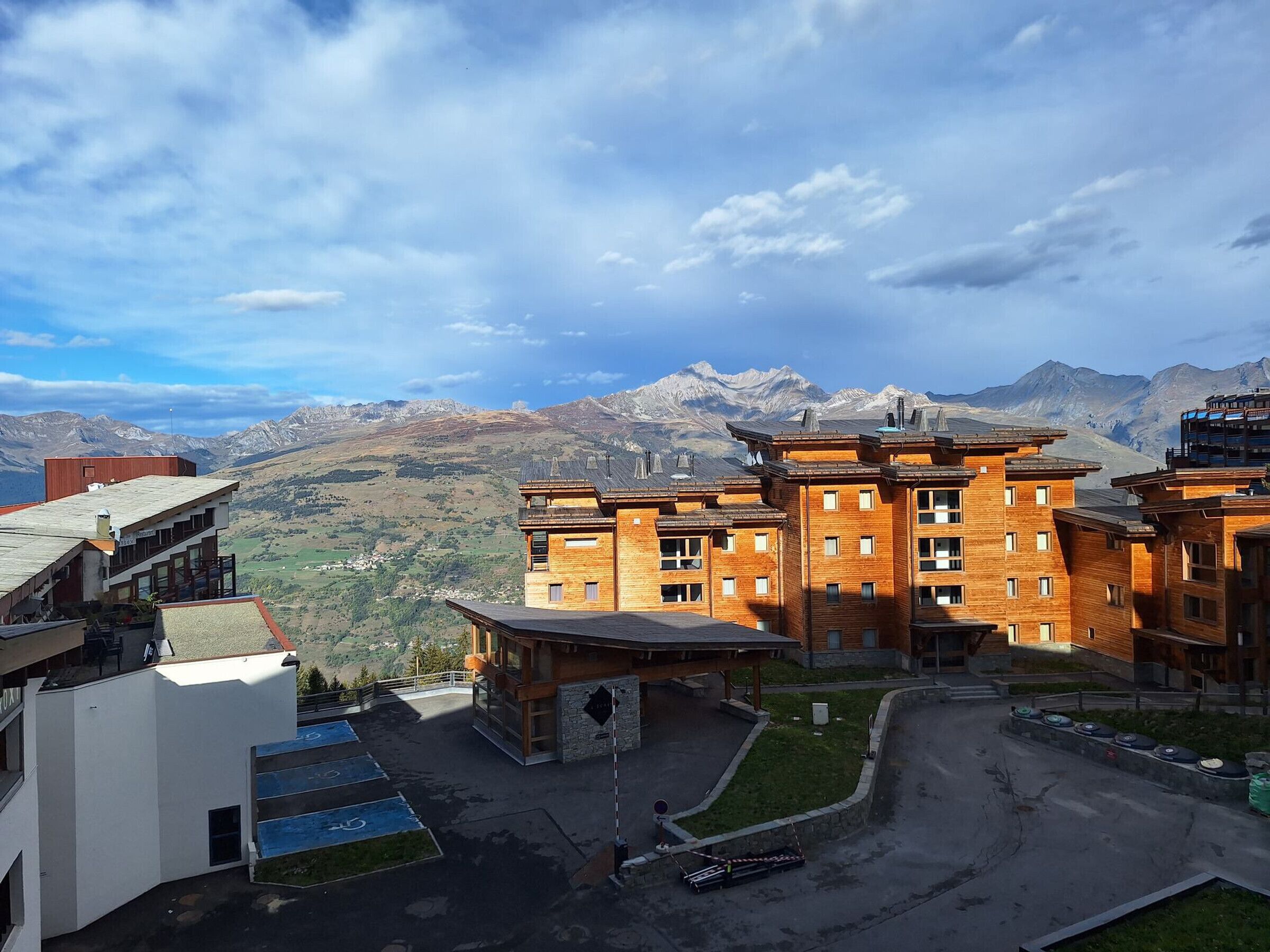 Un hôtel à plusieurs étages, de style architectural traditionnel, doté d’une cour intérieure et offrant une vue sur les montagnes.