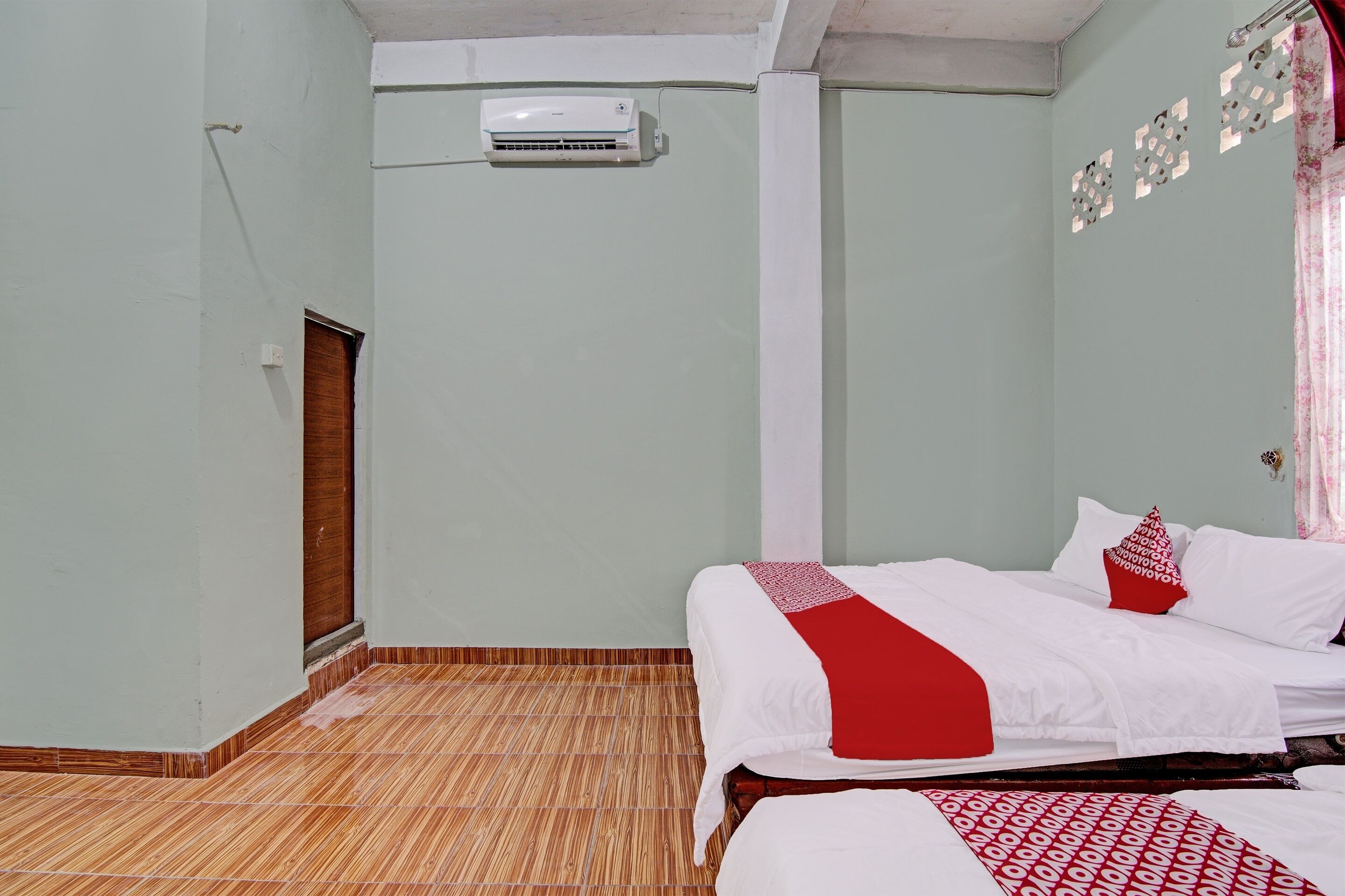 Een kamer met een bed, een wandairconditioner en een houten deur.