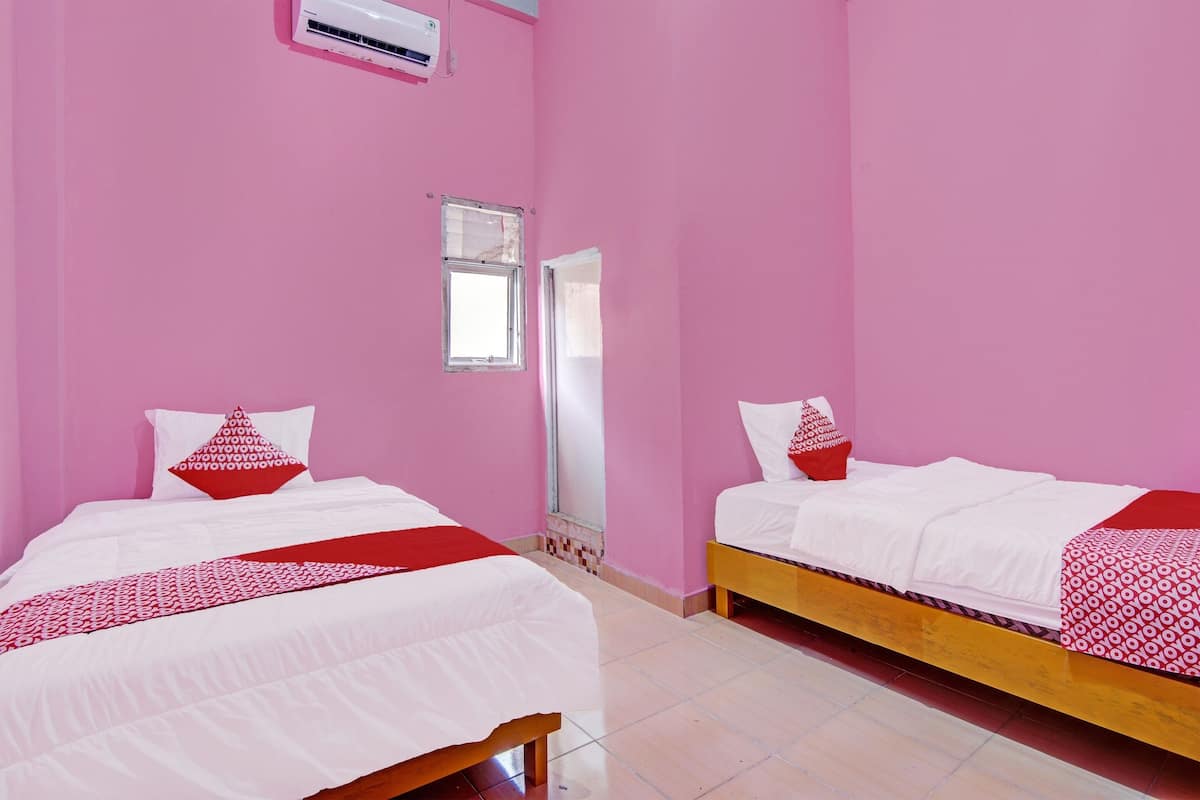 A room with two beds, pink walls, white bedding, and a small window.