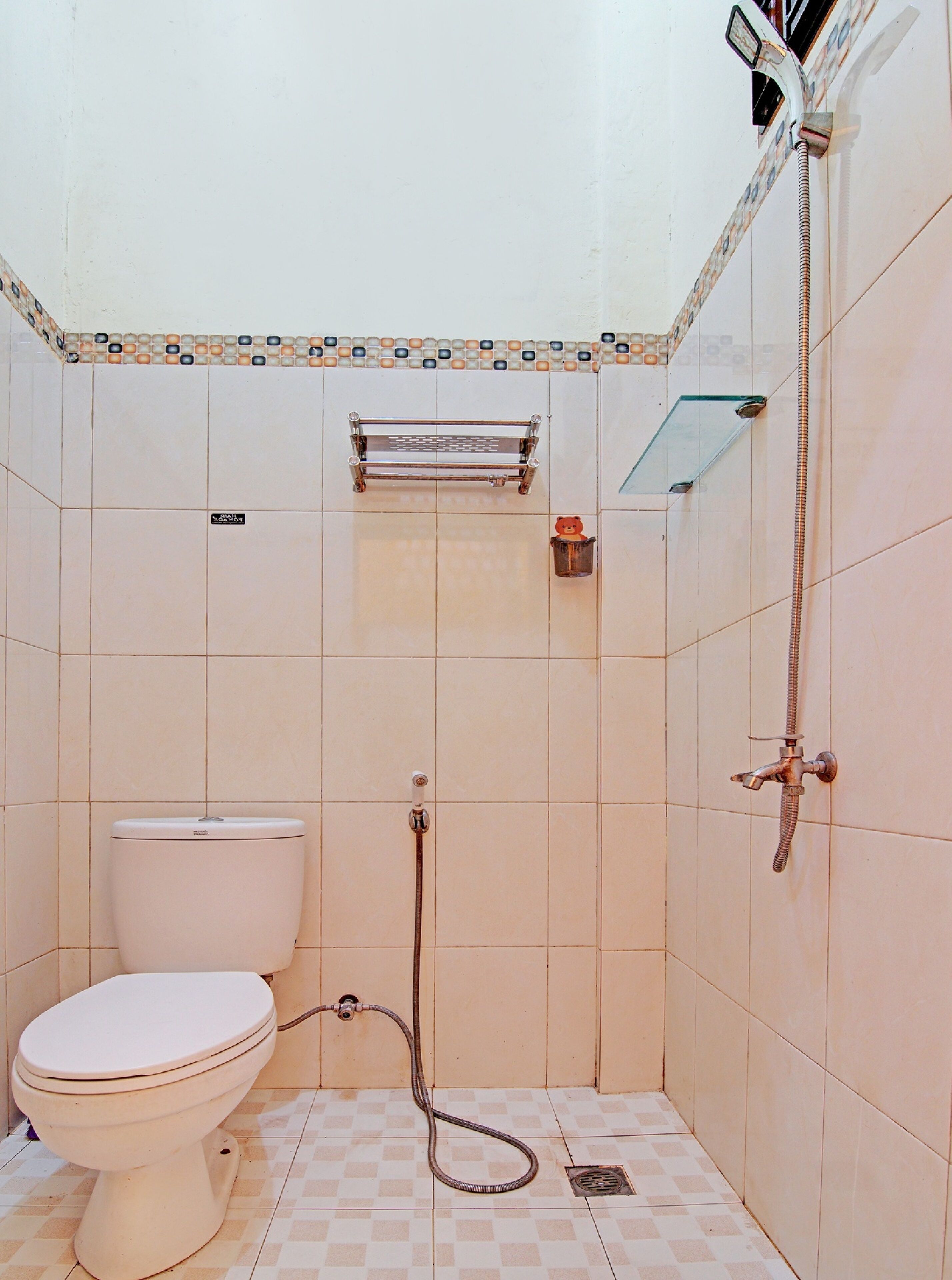 A small, tiled bathroom with a toilet, a shower, and a towel rack.