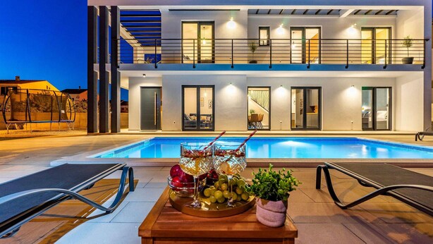 A modern two-story building with a swimming pool, outdoor seating, and a table with fruits and drinks. - Luxurious home in Zadar (Zadar)
