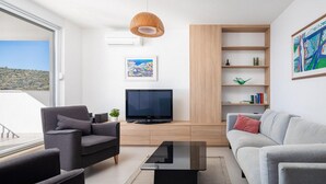 Un salon moderne avec un canapé, un fauteuil, une télévision et une bibliothèque.