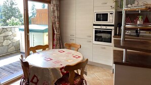 Una cocina con mesa de comedor, dos hornos, un microondas y una estufa integrada.