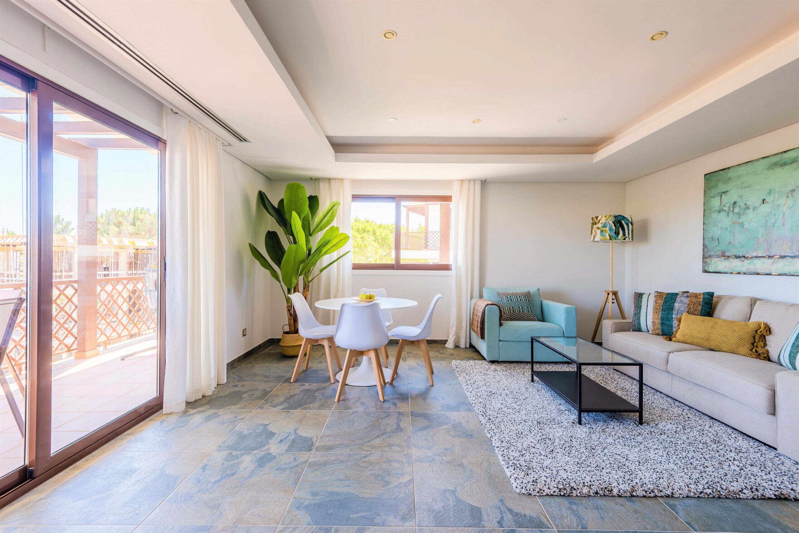 Una sala de estar moderna con comedor, ventanas amplias y vistas al exterior.