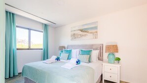 Una habitación de hotel con una cama grande, una mesita de noche con una lámpara y un cuadro en la pared.