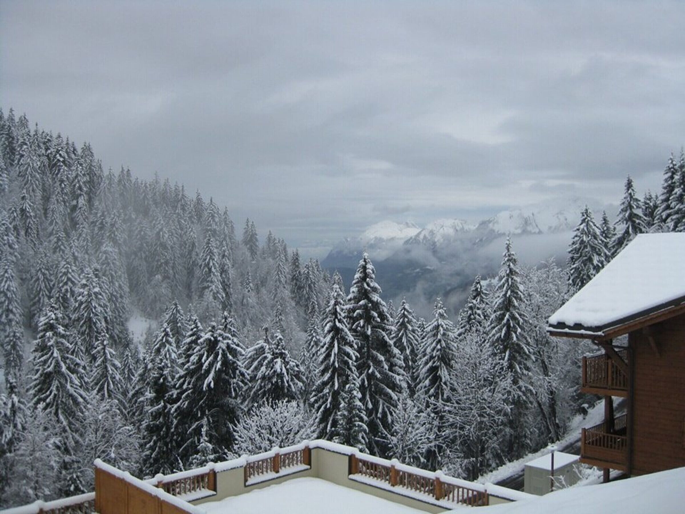A snowy mountain landscape with a cabin and a balcony.