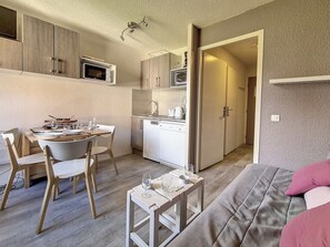 A compact living space with a dining area, kitchenette, and a sofa.