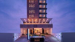A modern hotel entrance with a prominent sign, a covered walkway, and a staircase leading to the lobby.