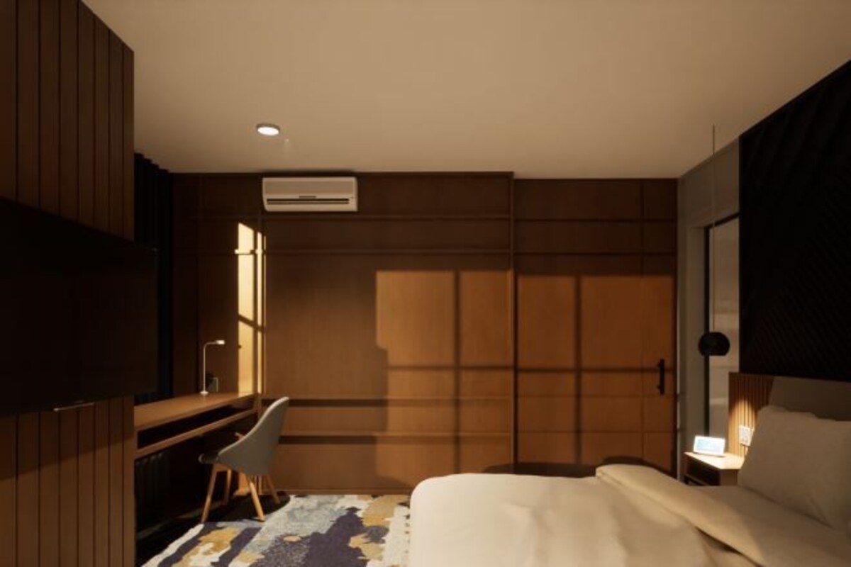 A hotel room with a bed, a desk, a chair, a TV, and a window.