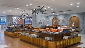 A modern buffet setup with a variety of food items, a wooden counter, and contemporary lighting fixtures.