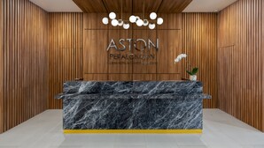 A reception desk with a marble top, wooden panel walls, and a ceiling with a hanging light fixture.