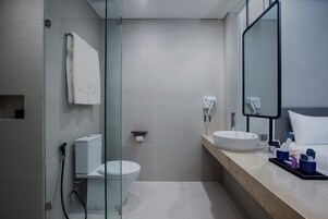 Un baño moderno con cabina de ducha de vidrio, inodoro, lavabo y espejo.