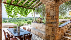 Eine Terrasse im Freien mit einer Steinmauer, einem Holztisch und Stühlen.