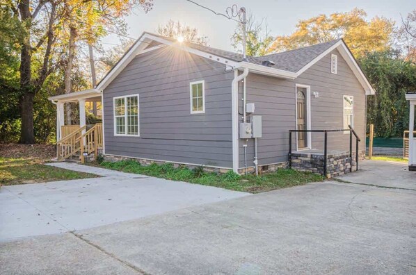 A single-story house with a front porch, a small attached garage, and a covered outdoor area.