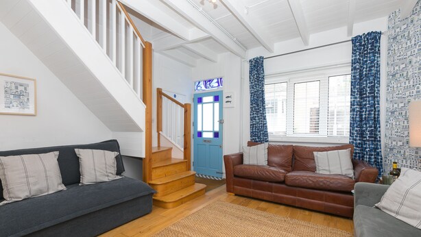 A living room with a staircase, two sofas, a coffee table, and a patterned wall. - Floyd’s, St Ives – Sleeps 8 – Dog Friendly – Off-Site Parking (St Ives)