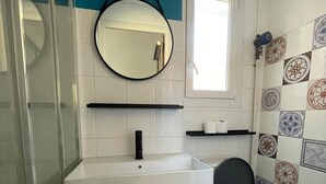 A bathroom with a toilet, sink, and mirror. - Appartement au Cœur du Centre Ville - T3 (Perpignan)