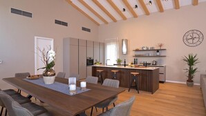 A modern kitchen with a central island, built-in appliances, and a dining area with a wooden table and grey chairs.