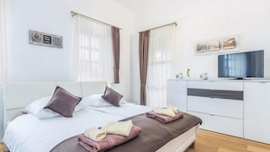 Ett modernt hotellrum med en stor säng, en TV och ett skrivbord.