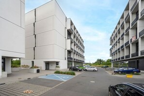 A modern building with a parking lot, marked handicap parking, and a blue bicycle lane. - Comfortable Studio | Balcony | Close to Airport (Wrocław)