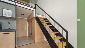 Un intérieur moderne avec un escalier, un plancher en bois et un coin cuisine comprenant un évier et des placards.