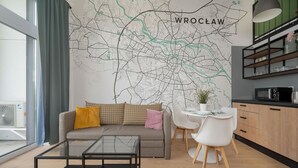 Un salon moderne avec un canapé, une table basse, une table à manger et des chaises. Une carte de Wrocław est accrochée au mur.
