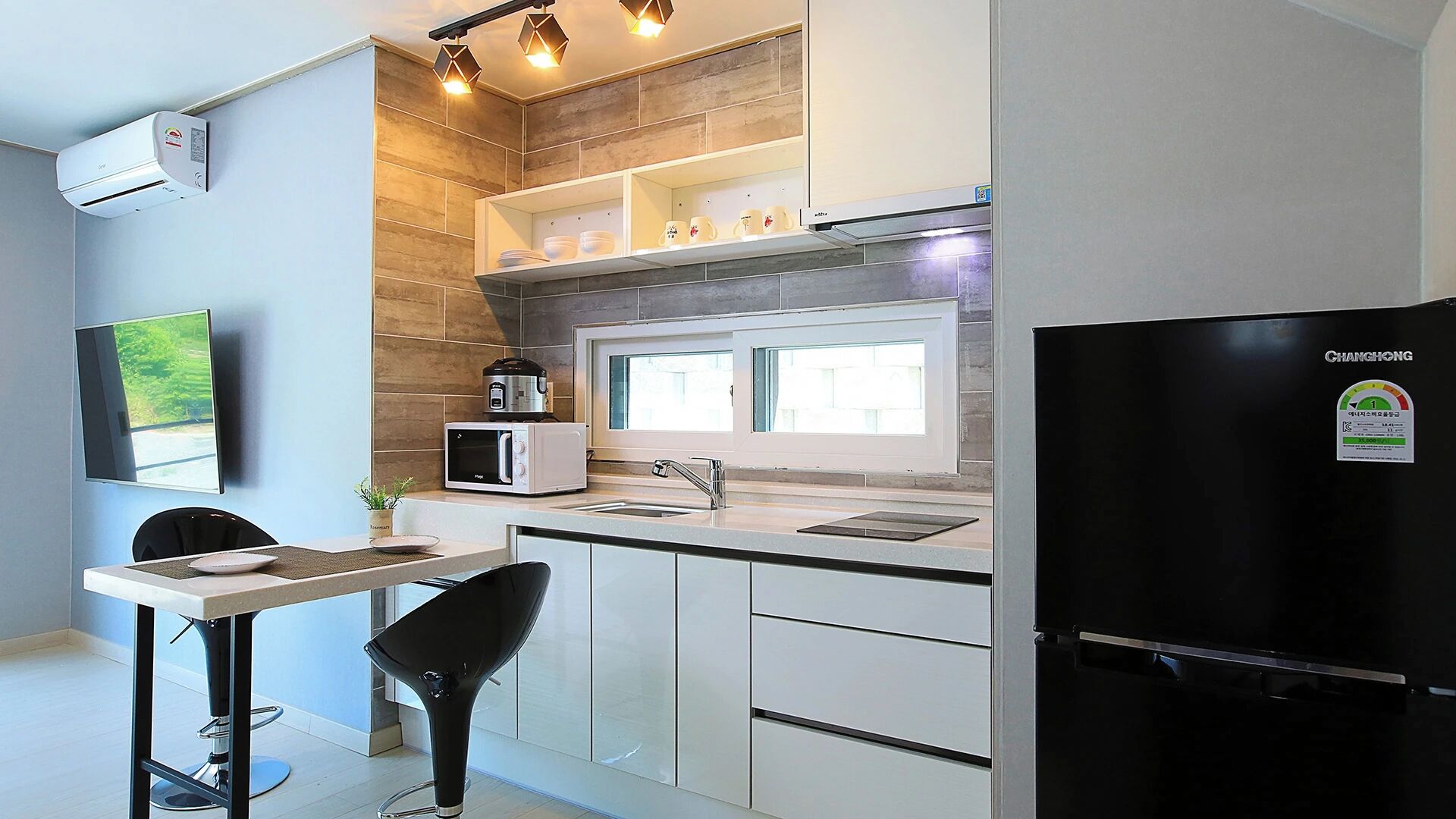 A modern kitchen with a built-in microwave, a coffee maker, and a refrigerator.