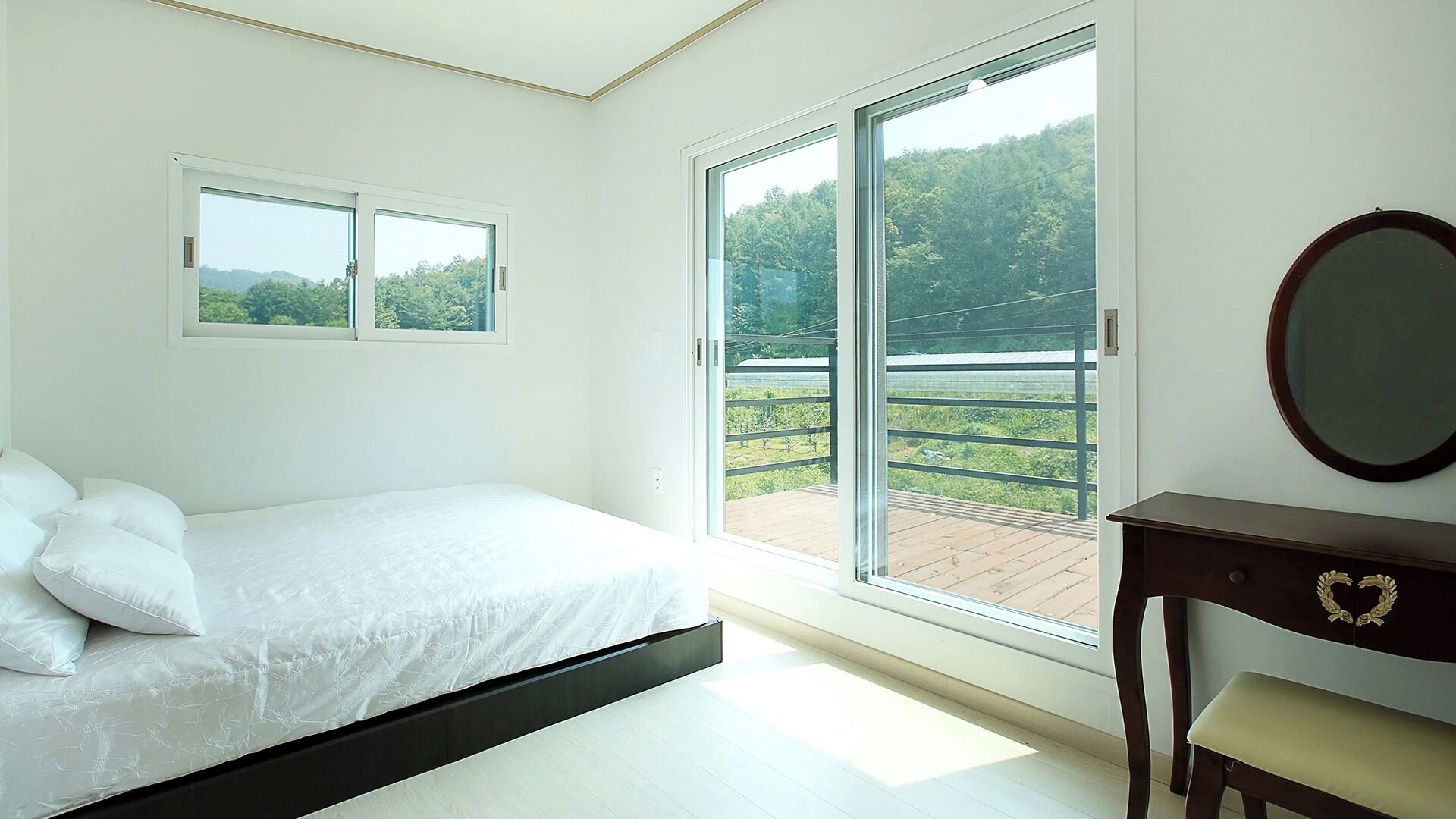 A bedroom with a bed, a dresser, a mirror, and a sliding glass door leading to an outdoor area.