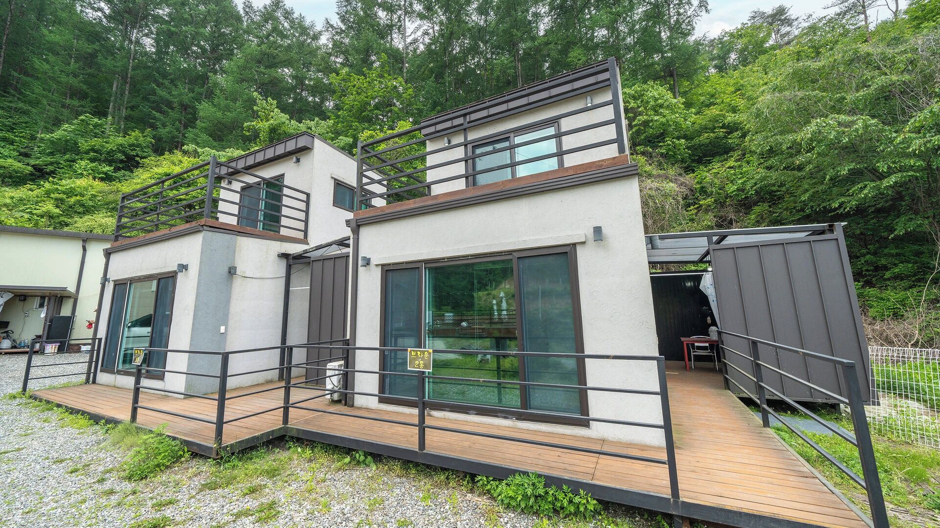 A modern two-story building with a wooden deck and glass doors.