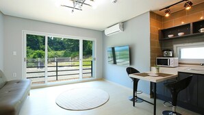 A modern kitchen with a dining area, a large window, and a view of greenery outside. - Hongcheon Stone Brown Pension (Hongcheon)