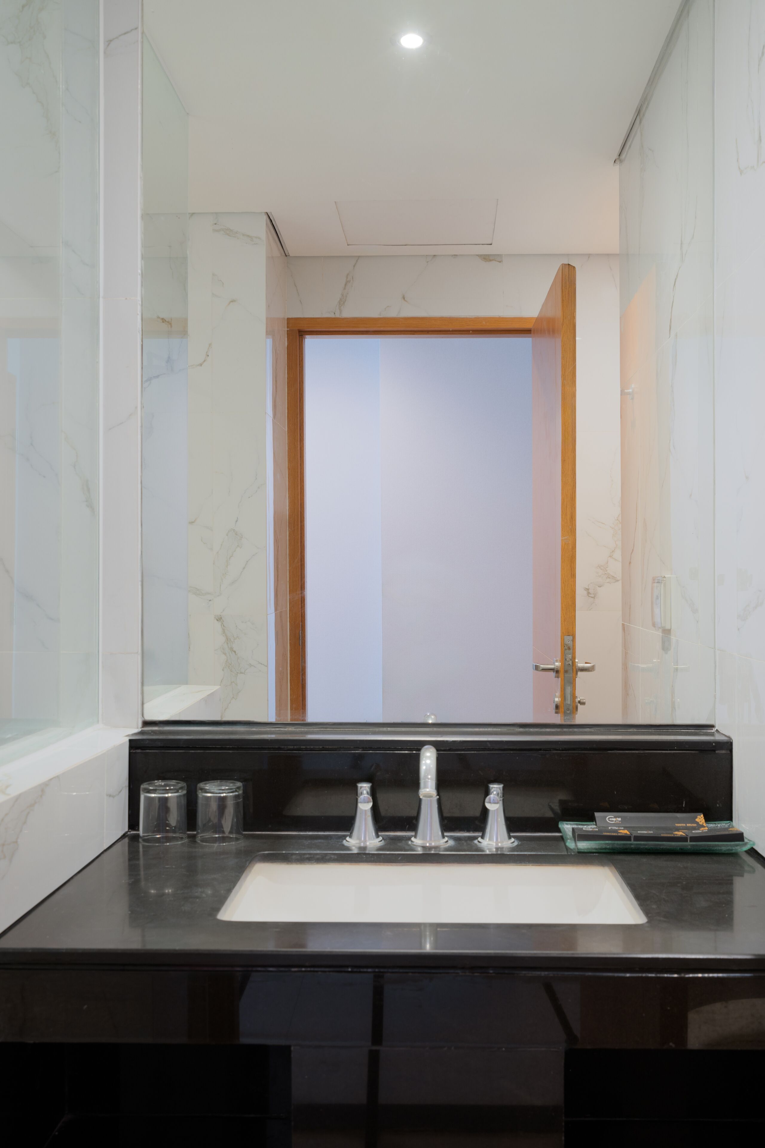 A modern bathroom with a black countertop, a white sink, and a mirror.