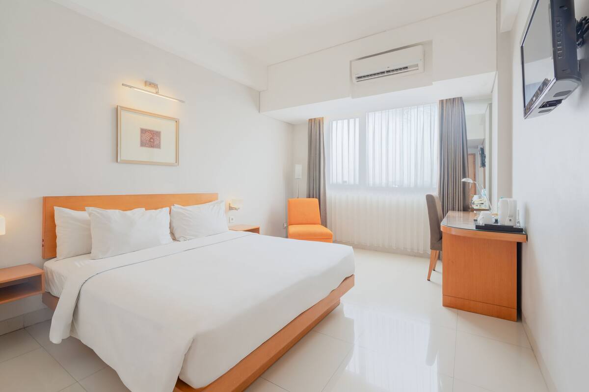Una habitación de hotel con una cama grande, un escritorio, una silla y un televisor.