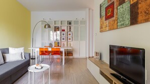 A modern living room with a sofa, a coffee table, a TV, and a dining area with a table and chairs. - Casa Limone by Wonderful Italy (Bologna)