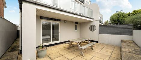 Propiedad residencial con patio, puerta corrediza de vidrio y pequeño jardín.