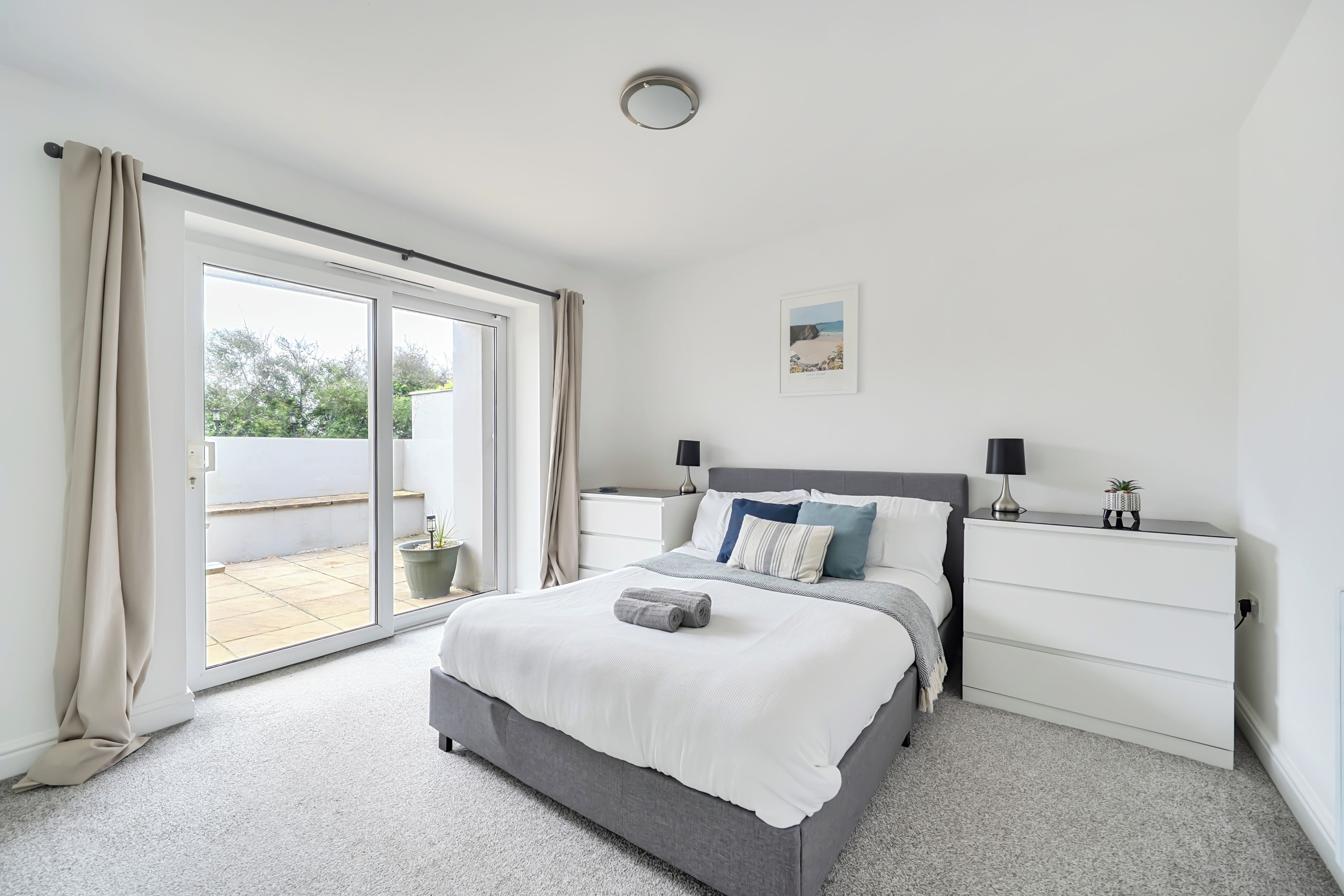 A bedroom with a bed, a nightstand, a lamp, and a picture on the wall.
