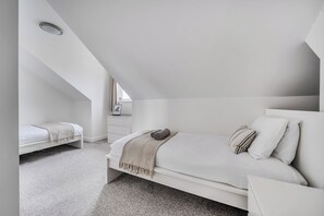A bedroom with a sloped ceiling, a bed with a headboard, a bedside table, and a window. - Spacious 3 Bed House - Sleeps 6 - Parking - Wifi (Newquay)