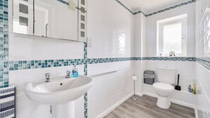 A bathroom with a white sink, a toilet, and a window. - Spacious 3 Bed House - Sleeps 6 - Parking - Wifi (Newquay)
