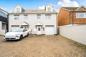 A two-story residential building with a car parked in the driveway. - Spacious 3 Bed House - Sleeps 6 - Parking - Wifi (Newquay)