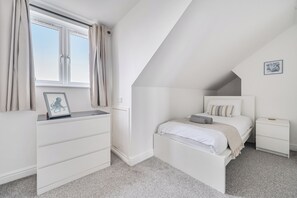 A bedroom with a bed, bedside tables, a dresser, a window with curtains, and a framed picture on the dresser. - Spacious 3 Bed House - Sleeps 6 - Parking - Wifi (Newquay)
