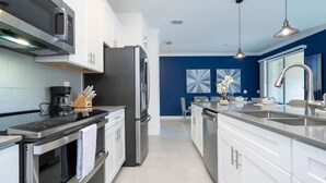 Een moderne keuken met roestvrijstalen apparatuur, witte kasten en een blauwe accentmuur.