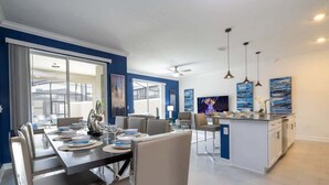 Een moderne eetruimte met een grote tafel gedekt voor een maaltijd, een keuken met een centraal eiland, en een zithoek.